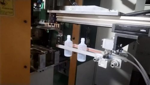 La máquina de moldeo por soplado produce una botella de enema con manipulador.